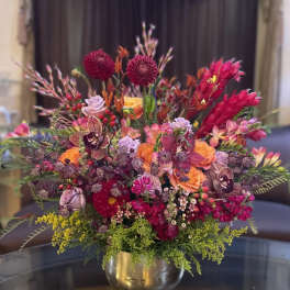 Colorful mixed flower arrangement in a gold vase