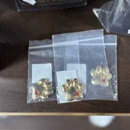 Three gold paw-print charms in clear plastic bags