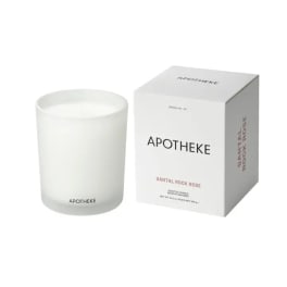 White scented candle in frosted glass jar beside matching Apotheke product box