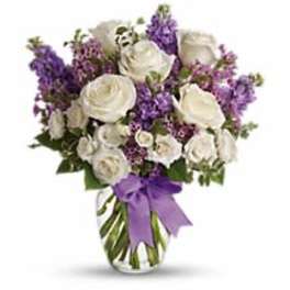 White rose and purple flower arrangement in a clear glass vase with a purple ribbon bow