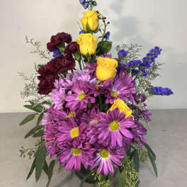 Tall bouquet of purple daisies, yellow roses, and dark red carnations