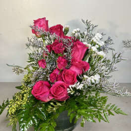 Pink roses arranged in a glass vase with white filler flowers