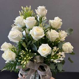 Medium vase arrangement of white roses with buds and a large silver ribbon bow.