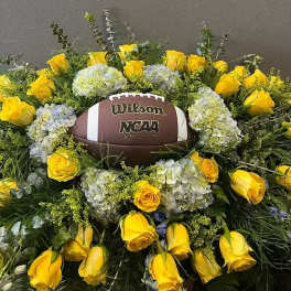 Yellow roses and pale hydrangeas arranged around a football centerpiece