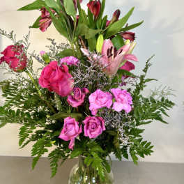 Pink roses and lilies arranged in a clear glass vase