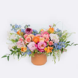 Mixed bouquet of pastel flowers in a tan vase