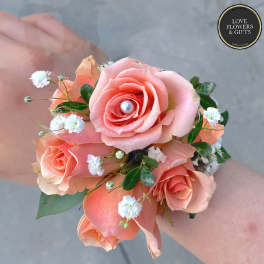 Peach rose wrist corsage with white filler flowers and a pearl accent.