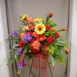 Colorful mixed flower arrangement on a black stand with a sheer ribbon