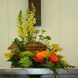 Tall floral arrangement with orange and yellow blooms in a basket