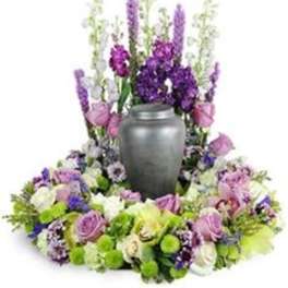 Purple and white floral funeral wreath around a gray urn