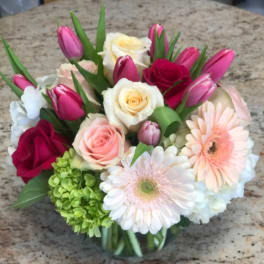 Mixed bouquet of roses, tulips, hydrangea, and gerbera daisies in a glass vase