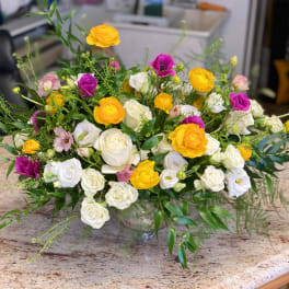 Mixed bouquet of white, yellow, and purple roses in a glass vase