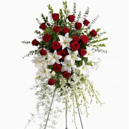 Standing floral spray with red roses and white lilies on a metal easel