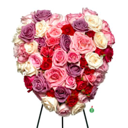Heart-shaped arrangement of pink, red, lavender, and cream roses on a metal easel stand