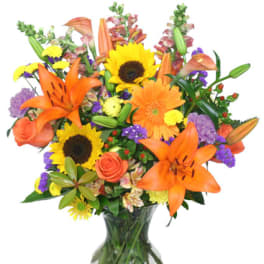 Bright mixed bouquet with sunflowers, orange lilies, and roses in a glass vase