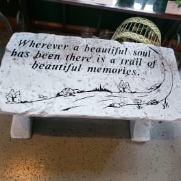 Decorative stone bench with a memorial quote painted on it