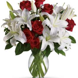 Red roses and white lilies arranged in a clear glass vase