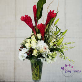 Tall tropical bouquet in a glass vase with red ginger and white roses
