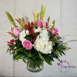 Pink roses and white hydrangeas in a glass vase with red berries
