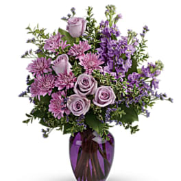 Lavender roses and purple flowers in a purple glass vase