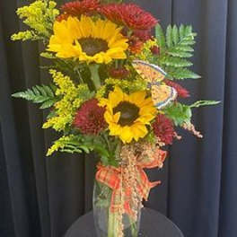 Sunflower bouquet in a clear glass vase with red and yellow accents