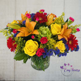 Colorful bouquet of roses, lilies, and gerbera daisies in a glass vase
