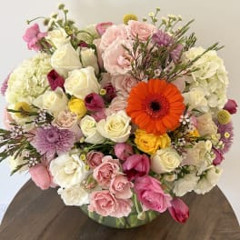 Mixed bouquet of pink, white, and yellow flowers in a glass vase