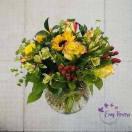 Bouquet of yellow roses and sunflowers in a clear glass vase
