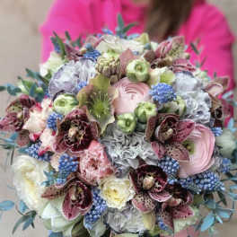 Pastel bouquet with orchids, ranunculus, and blue berry-like accents