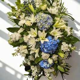 Large floral standing spray with blue hydrangeas, white lilies, and white blooms