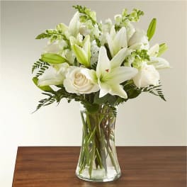 White lilies and roses arranged in a clear glass vase