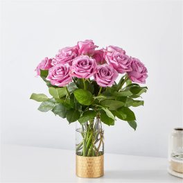 Pink roses arranged in a clear glass vase with a gold base