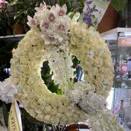 Large white floral wreath with orchids and roses on a stand