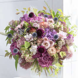 Large bouquet of pink and purple flowers in a white vase