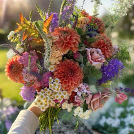 Handheld bouquet of mixed colorful flowers in sunlight