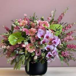 Pink mixed bouquet with orchids and gerbera daisies in a black vase