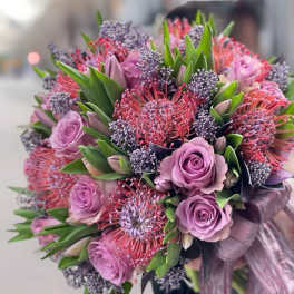 Lavender roses and pink pincushion protea bouquet with green foliage