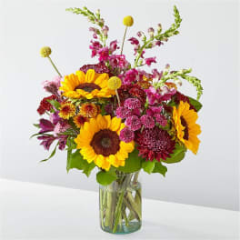 Bouquet of sunflowers and mixed pink flowers in a glass vase