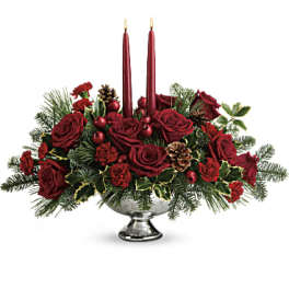 Red rose centerpiece with two lit taper candles in a silver bowl