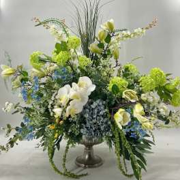 Large floral arrangement in a silver urn with white orchids and green blooms