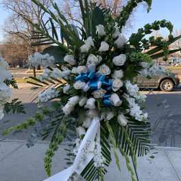 Large white rose standing spray with blue ribbon and greenery