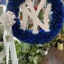 Blue floral wreath with a white monogram and ribbon bow on an easel
