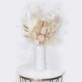 Cream dried floral arrangement in a white vase on a round table