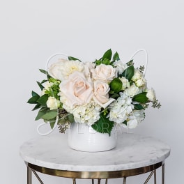 White and blush roses arranged in a white vase