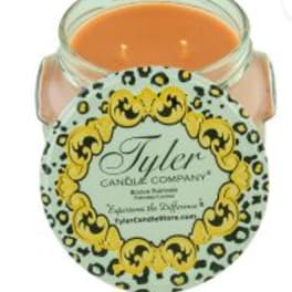 Orange candle in a glass jar with a decorative label
