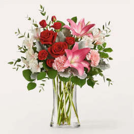 Bouquet of red roses and pink lilies in a clear glass vase
