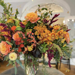 Mixed orange and purple floral arrangement in a clear glass vase