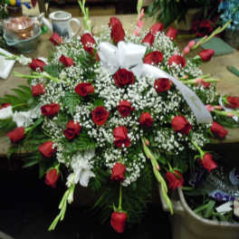 Large red rose and white lily floral spray with a white ribbon