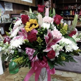 Mixed bouquet in a vase with roses, lilies, sunflowers, and carnations
