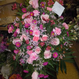 Pink roses and carnations arranged in a large standing spray